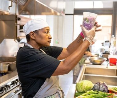 Chef examinant un récipient au milieu de légumes frais en cuisine