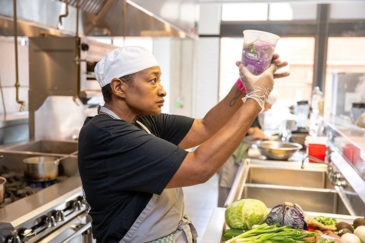 Chef examinant un récipient au milieu de légumes frais en cuisine